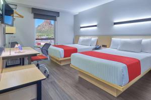 a hotel room with two beds and a desk at City Express by Marriott Guaymas in Guaymas