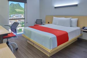 Un dormitorio con una cama y un escritorio y una ventana. en City Express by Marriott Guaymas, en Guaymas