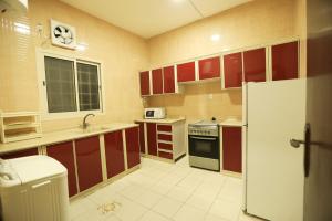 eine Küche mit roten Schränken und einem weißen Kühlschrank in der Unterkunft العيرى للشقق المخدومه جيزان 3 in Dschāzān
