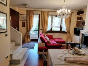ein Wohnzimmer mit einem roten Sofa und einem Kronleuchter in der Unterkunft La Bouganville - Holiday house with garden Forte Dei Marmi, Toscana in Forte dei Marmi