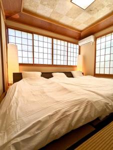 a large white bed in a room with windows at R House 川越 in Kawagoe