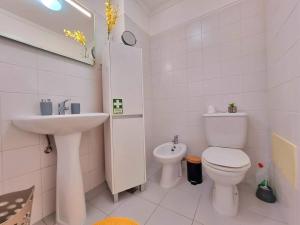 a white bathroom with a toilet and a sink at Junto ao Mar - Apartamento T1 in Santa Cruz