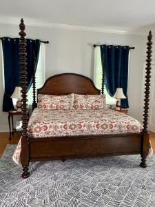 a bedroom with a wooden bed with blue curtains at Charred Oaks Inn in Versailles