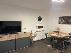 ein Wohnzimmer mit einem Tisch, einem TV, einem Tisch und einer Uhr in der Unterkunft Roségold in Bad Harzburg