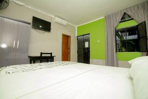 um quarto com uma cama branca e uma parede verde em Hostal Los Helechos Tarapoto em Tarapoto