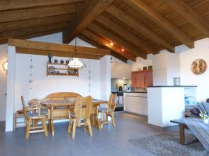 eine Küche und ein Esszimmer mit einem Holztisch und Stühlen in der Unterkunft Ferienwohnung Laax mit Traumblick, großem Balkon und Terrasse in Laax
