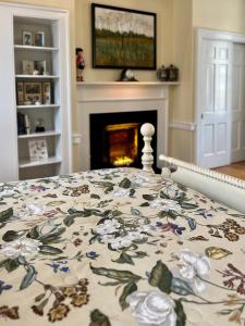 a bed with a floral bedspread on it with a fireplace at Charred Oaks Inn in Versailles