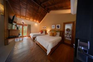 a bedroom with two beds and a television in it at Alta Gracia Parque Hotel in Caacupé