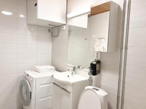a white bathroom with a toilet and a sink at Rollo Apartments in Rovaniemi