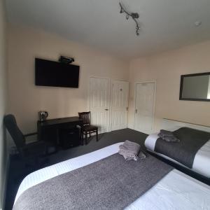 a bedroom with two beds and a desk and a television at The Beath Inn in Cowdenbeath