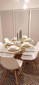 uma mesa de jantar com cadeiras brancas e uma mesa de vidro em "Dad and Daughter Weekend House" em Rūdaičiai
