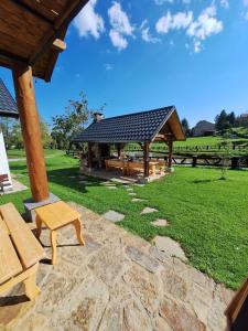 a pavilion with a picnic table and benches in a field at Domki Nad Liliowym Stawem in Berezka