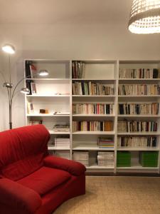 Maison confortable et calme/5 chambres & 6 SdB في تولوز: غرفة معيشة مع أريكة حمراء ورفوف الحجز