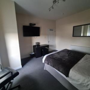 a bedroom with a bed and a tv on the wall at The Beath Inn in Cowdenbeath