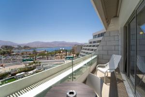 a balcony with a table and chairs and a view of the ocean at Sea Side Eilat Vacation Apartment in Eilat