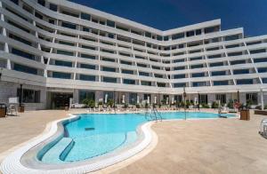 a large building with a swimming pool in front of it at Sea Side Eilat Vacation Apartment in Eilat