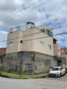 een witte auto geparkeerd voor een gebouw met graffiti bij NPousadas in Belo Horizonte