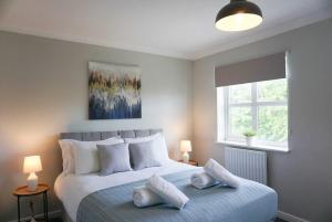 een slaapkamer met een bed met kussens en een raam bij Oak House - Spacious Townhouse, FREE gated parking, perfect for corporate, contractor & Leisure guests in Bedford