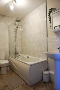 a bathroom with a tub and a toilet and a sink at Oak House - Spacious Townhouse, FREE gated parking, perfect for corporate, contractor & Leisure guests in Bedford