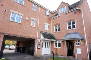 a large red brick building with a garage at Oak House - Spacious Townhouse, FREE gated parking, perfect for corporate, contractor & Leisure guests in Bedford