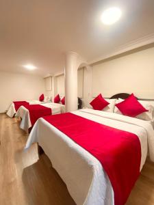two beds in a room with red and white sheets at Hotel Fontibon in Bogotá