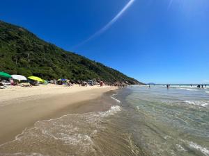 una playa con gente y sombrillas y el océano en Férias na Praia dos Ingleses, en Florianópolis