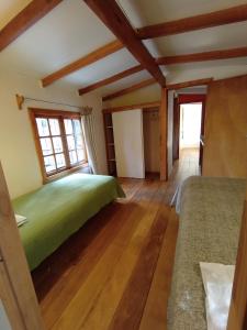 1 dormitorio en una cabaña de madera con cama y ventanas en Hostal Repu, en Pucón