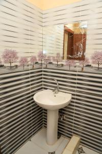 a bathroom with a sink in a room with trees at Elamier House in Al Aqālitah