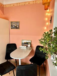 une table et des chaises dans une pièce avec un mur rose dans l'établissement K-Apartment, à Riga