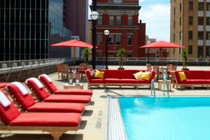 a pool with red chairs and umbrellas on a rooftop at Renaissance Columbus Downtown Hotel in Columbus