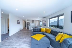 a living room with a blue couch and yellow pillows at Kirimoko Family Retreat in Wanaka