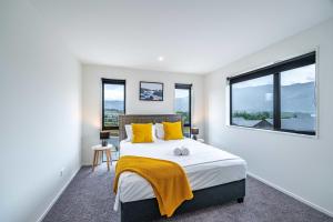 a bedroom with a bed with yellow pillows and a window at Kirimoko Family Retreat in Wanaka