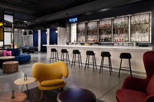 a bar with a yellow chair and tables and chairs at Aloft Orlando International Drive in Orlando