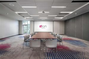 a conference room with a table and chairs and a screen at Aloft Orlando International Drive in Orlando