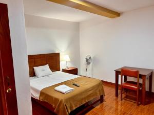 HOTEL LOS ANDES SUITE في تروخيو: غرفة نوم بسرير مع مكتب وكرسي