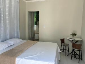 a bedroom with a bed and a table and chairs at Suítes Moinho in Cabo Frio