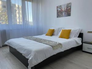 布加勒斯特的住宿－Apartament Bucuresti Bucharest，一间卧室配有带白色床单和黄色枕头的床。