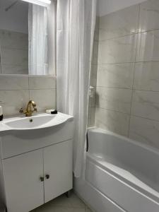 a white bathroom with a sink and a bath tub at Apartament Bucuresti Bucharest in Bucharest