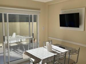 a dining room with a table and a tv on the wall at Caracolas Departamentos in San Clemente del Tuyú
