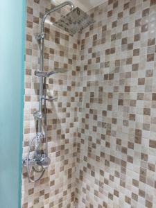 een douche in de badkamer met bruine en witte tegels bij Cozy Loft in Tbilisi City