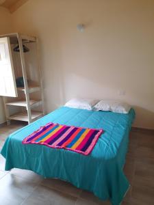 a bed with a colorful blanket on top of it at Habitación con baño privado in Barichara