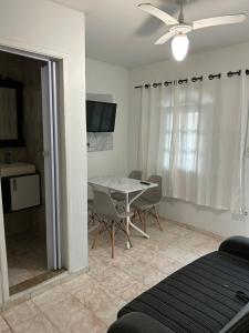 a bedroom with a table and chairs and a ceiling fan at Suítes Moinho in Cabo Frio