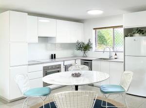 une cuisine avec des placards blancs et une table et des chaises blanches dans l'établissement Holiday Chic Close to Beach & CBD, à Perth