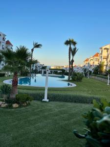 una piscina in un cortile con palme e edifici di Le cocon doré - à deux pas de la plage a Cabo Negro