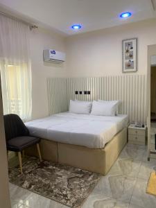 een slaapkamer met een groot bed en een stoel bij Bott Extended Stay in Abuja