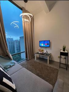 ein Wohnzimmer mit einem großen Fenster und einem Fernseher in der Unterkunft Nebulosa @ Empire Damansara in Petaling Jaya