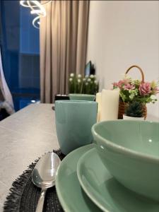 ein Tisch mit grünen Schalen, einem Löffel und Blumen in der Unterkunft Nebulosa @ Empire Damansara in Petaling Jaya
