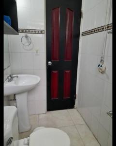 a bathroom with a red door and a toilet and a sink at R.3-3 Lindo estudio, 2 habitaciones en el ciudad de Panamá. in Panama City