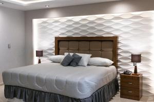 1 dormitorio con 1 cama grande y pared blanca en Hotel Arthemisa, en Guanajuato