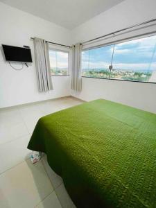 um quarto com uma cama verde e uma grande janela em Casa Moderna em Escarpas do Lago em Capitólio